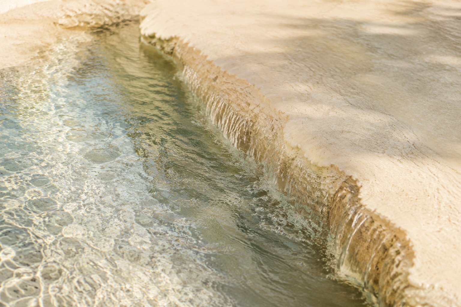 Agua clara que fluye suavemente sobre piedra caliza de tonos crema